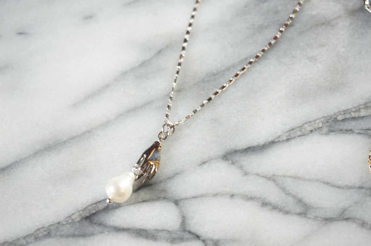 Hand holding pearl-drop necklace / Teardrop Pearl and hands dainty necklace