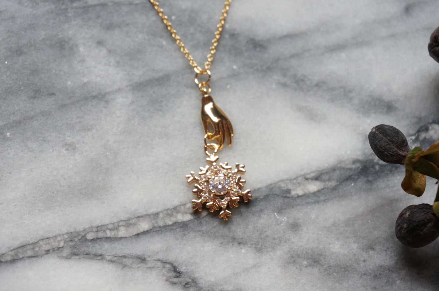 NEVE Gold Plated Hand Holding Snowflake Necklace
